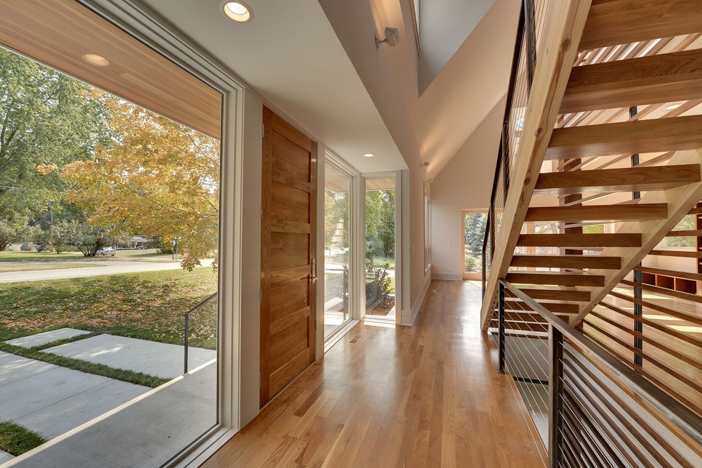 Modelo de entrada contemporánea con paredes beige, suelo de madera en tonos medios, puerta simple y puerta de madera en tonos medios