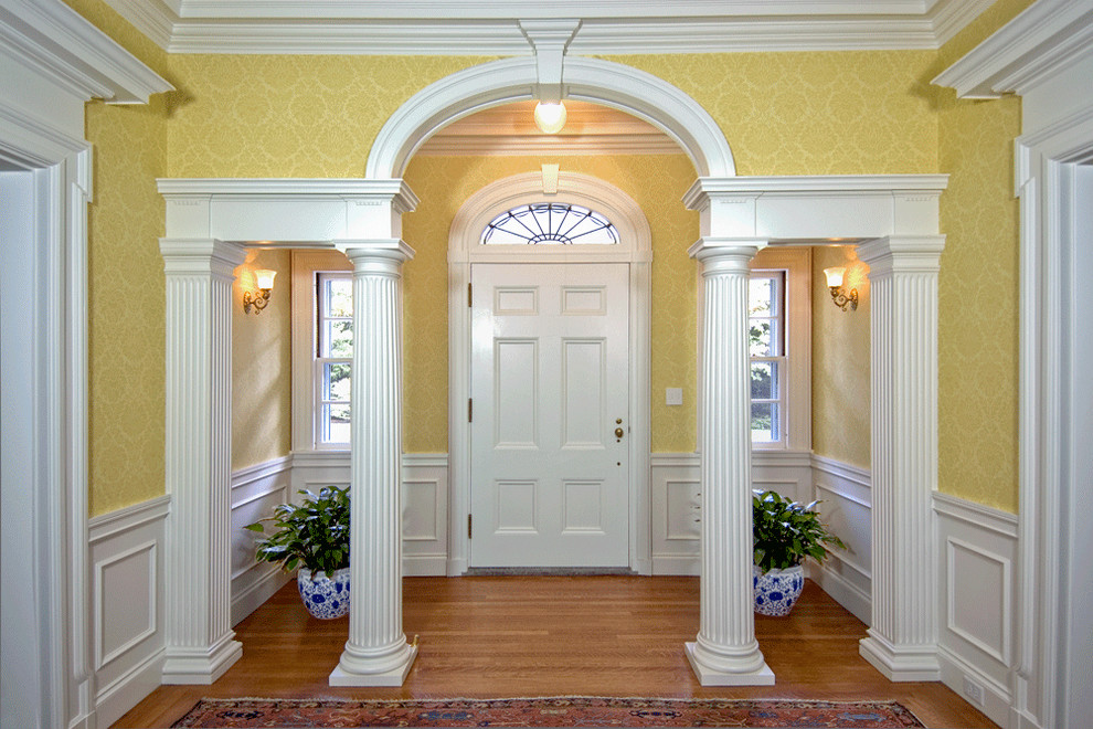 Идея дизайна: большая входная дверь в классическом стиле с желтыми стенами, паркетным полом среднего тона, одностворчатой входной дверью и белой входной дверью