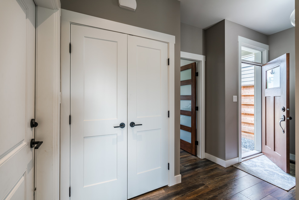 На фото: входная дверь среднего размера в стиле модернизм с серыми стенами, паркетным полом среднего тона, одностворчатой входной дверью, входной дверью из дерева среднего тона и коричневым полом