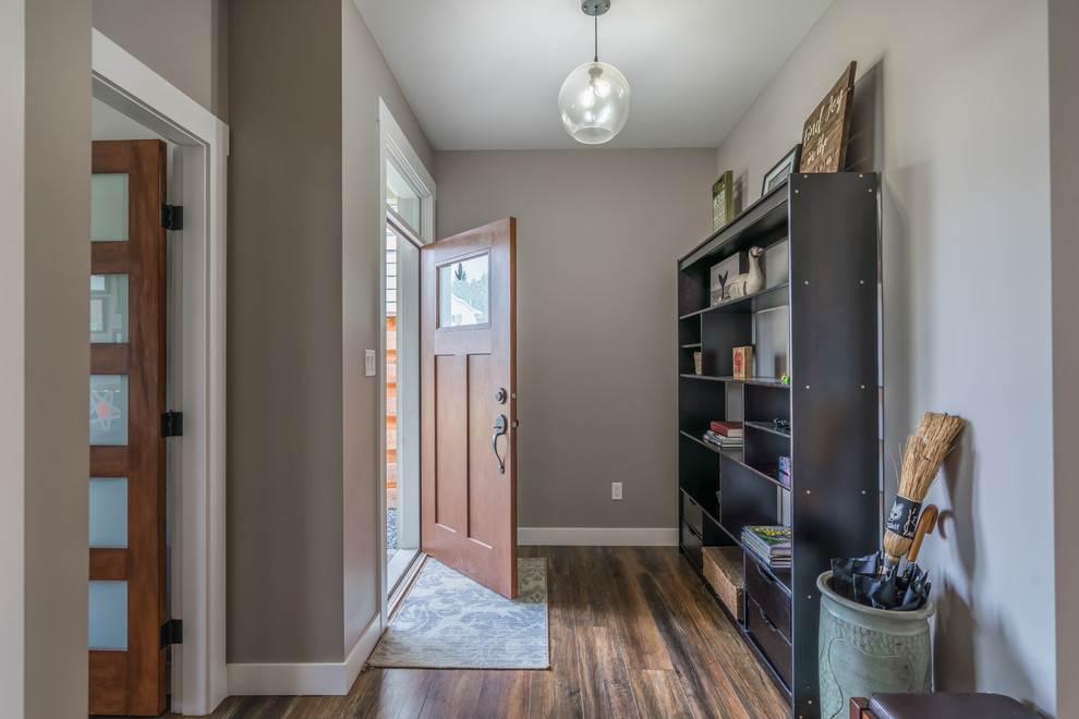 Réalisation d'une porte d'entrée minimaliste de taille moyenne avec un mur gris, un sol en bois brun, une porte simple, une porte en bois brun et un sol marron.