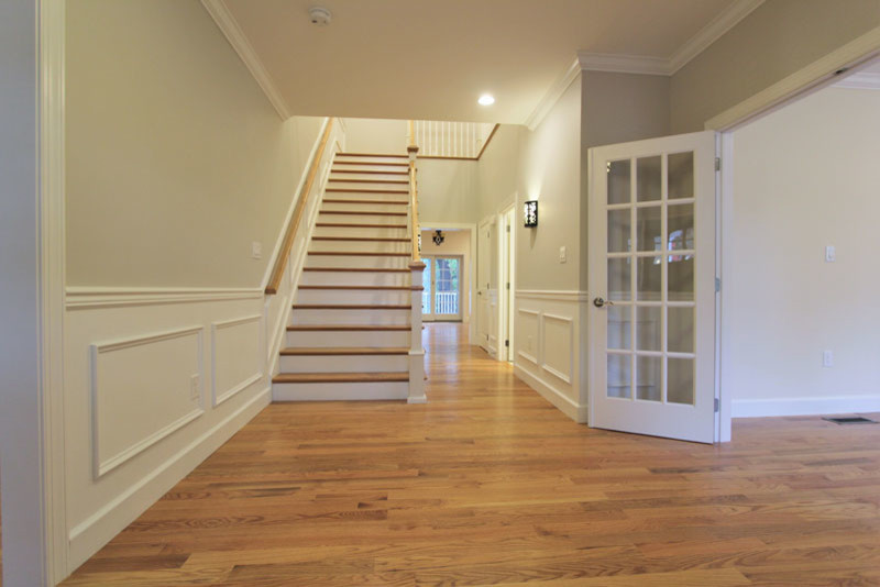 Esempio di un corridoio classico di medie dimensioni con pareti beige, pavimento in legno massello medio, una porta singola, una porta nera e pavimento beige