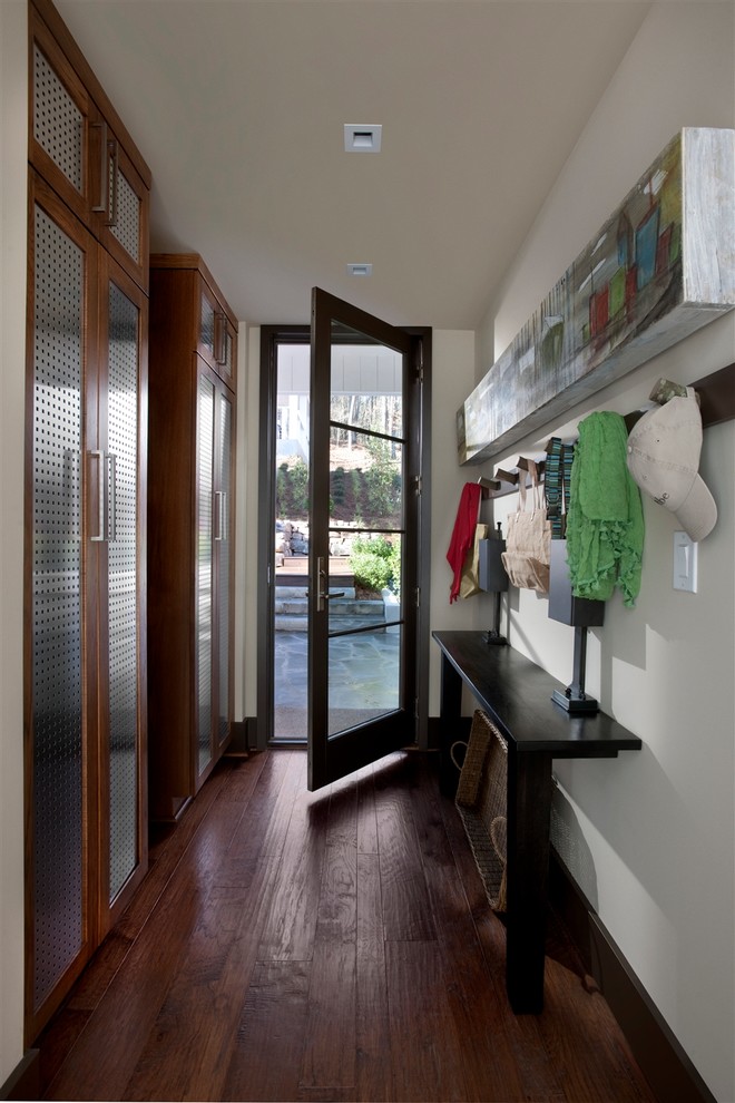 На фото: узкая прихожая среднего размера в стиле неоклассика (современная классика) с белыми стенами, темным паркетным полом, одностворчатой входной дверью, стеклянной входной дверью и коричневым полом с