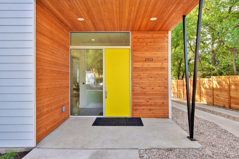 На фото: входная дверь среднего размера в стиле модернизм с бетонным полом, одностворчатой входной дверью, желтой входной дверью и серым полом