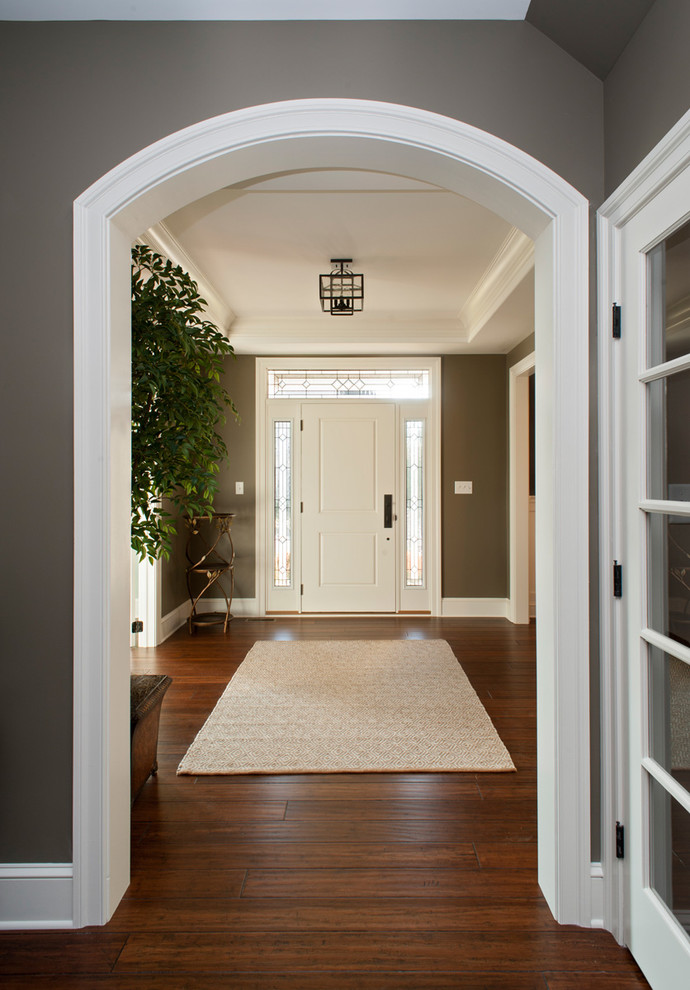 Foto di un grande ingresso classico con pareti grigie, pavimento in legno massello medio, una porta singola e una porta bianca