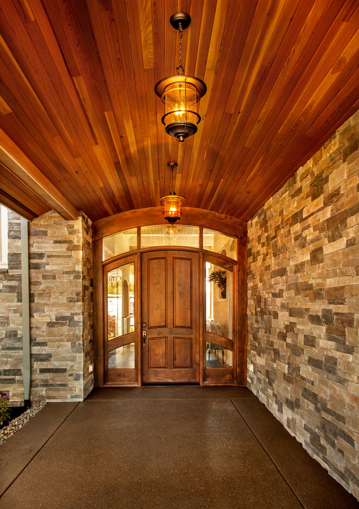Idée de décoration pour une très grande porte d'entrée tradition avec un mur multicolore, sol en béton ciré, une porte simple et une porte en bois brun.