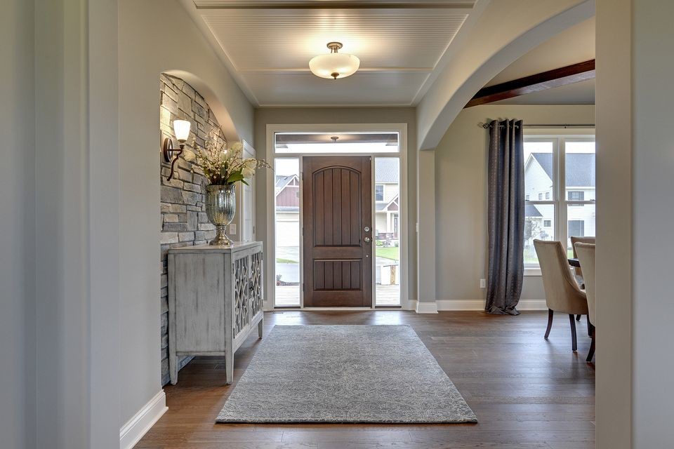 Cette image montre un hall d'entrée traditionnel de taille moyenne avec un mur gris, un sol en bois brun, une porte simple et une porte en bois foncé.