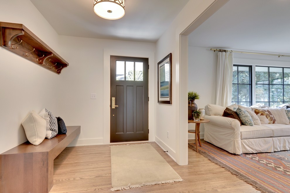 Example of an eclectic medium tone wood floor entryway design in Minneapolis with white walls and a black front door