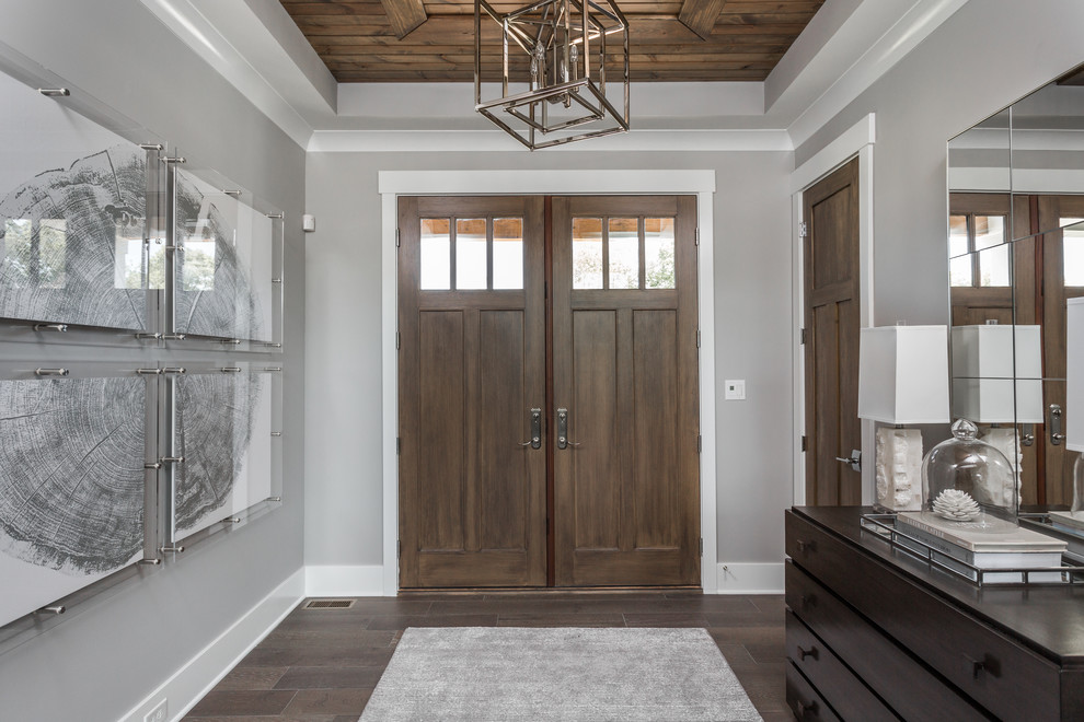 Exemple d'une porte d'entrée tendance de taille moyenne avec un mur gris, parquet foncé, une porte double, une porte en bois foncé et un sol marron.