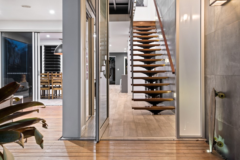 Photo of a large urban foyer in Other with brown walls, a pivot front door and a grey front door.