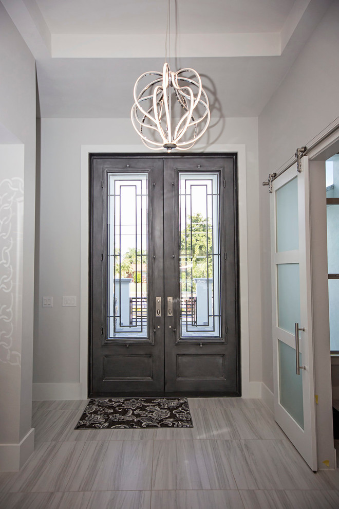 Immagine di un grande ingresso minimalista con pareti bianche, pavimento in marmo, una porta a due ante e una porta grigia