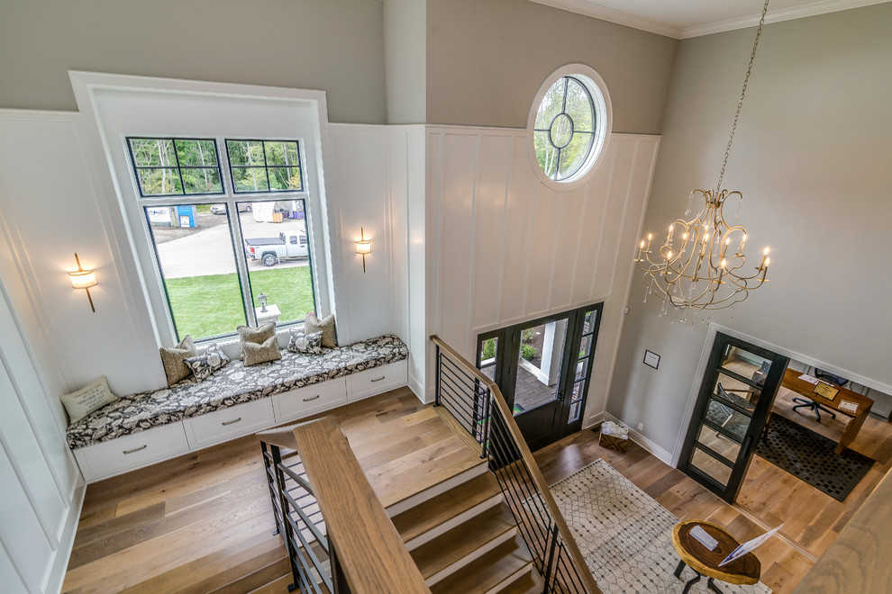 This is an example of a large traditional foyer in Cleveland with grey walls, light hardwood flooring, a single front door, a glass front door and brown floors.
