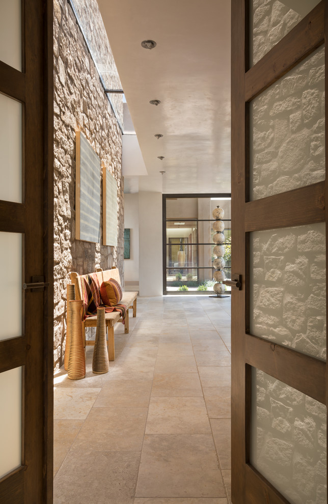アルバカーキにあるラグジュアリーな中くらいなサンタフェスタイルのおしゃれな玄関ドア (ベージュの壁、木目調のドア、ベージュの床、トラバーチンの床) の写真