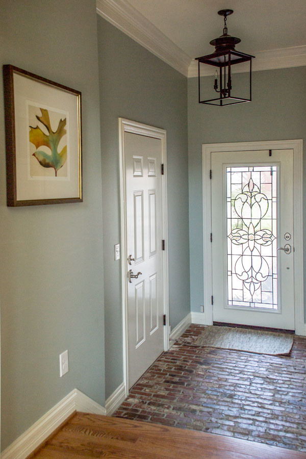 Inredning av ett klassiskt mellanstort kapprum, med grå väggar, tegelgolv, en enkeldörr, en vit dörr och rött golv