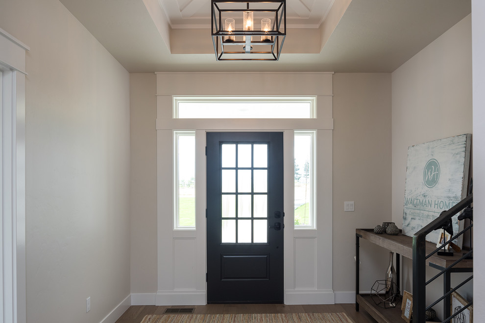 Стильный дизайн: входная дверь среднего размера в классическом стиле с бежевыми стенами, паркетным полом среднего тона, одностворчатой входной дверью, черной входной дверью и коричневым полом - последний тренд