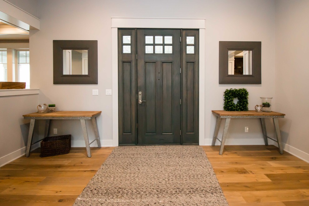 Cette photo montre une porte d'entrée nature de taille moyenne avec un mur gris, parquet clair, une porte simple, une porte en bois foncé et un sol marron.