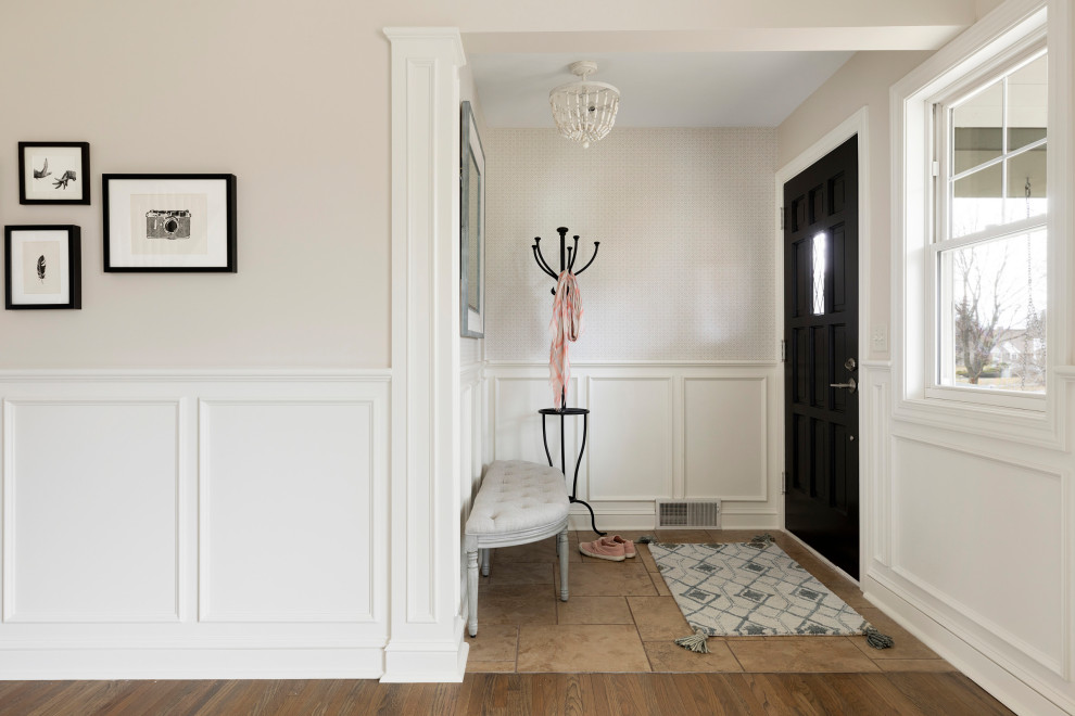 Cette photo montre un petit hall d'entrée chic avec un mur beige, un sol en carrelage de porcelaine, une porte simple, une porte noire et un sol marron.