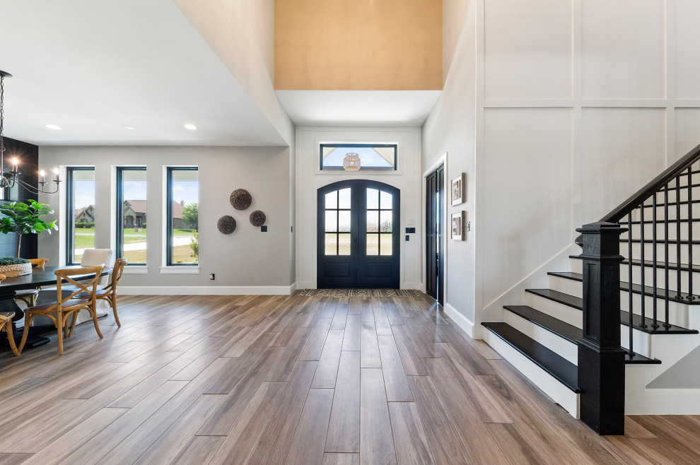 Mittelgroße Country Haustür mit grauer Wandfarbe, braunem Holzboden, Doppeltür, schwarzer Haustür, buntem Boden und vertäfelten Wänden in Dallas