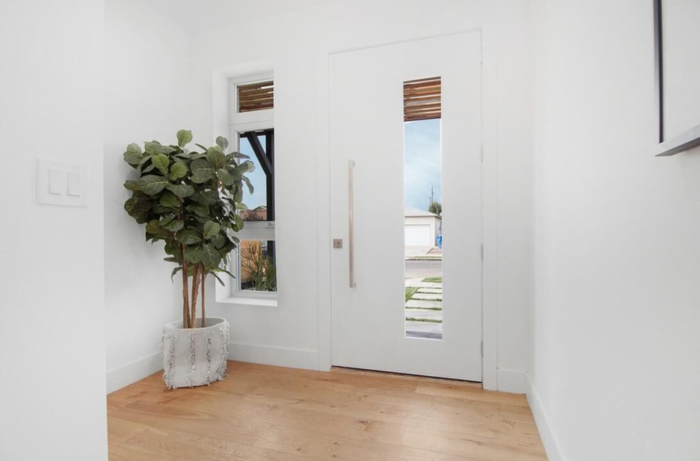 Idee per una porta d'ingresso minimalista di medie dimensioni con pareti bianche, parquet chiaro, una porta a pivot, una porta bianca e pavimento beige