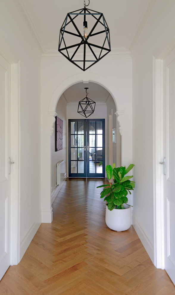 Ispirazione per un grande corridoio vittoriano con pareti bianche, pavimento in legno massello medio, una porta singola e una porta nera