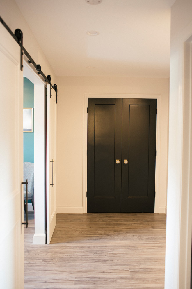 Diseño de puerta principal urbana de tamaño medio con paredes blancas, suelo de madera clara, puerta doble y puerta negra
