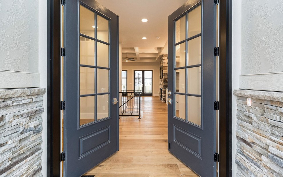 他の地域にあるお手頃価格の中くらいなトランジショナルスタイルのおしゃれな玄関ドア (グレーの壁、淡色無垢フローリング、青いドア) の写真