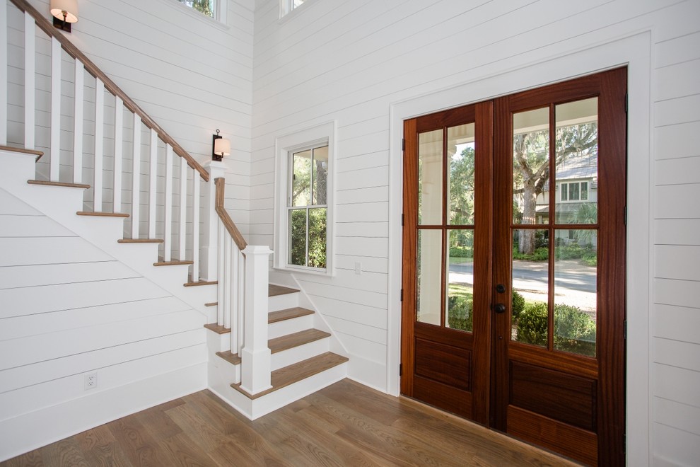 Imagen de puerta principal campestre grande con paredes blancas, suelo de madera en tonos medios, puerta doble, puerta de madera en tonos medios y suelo marrón