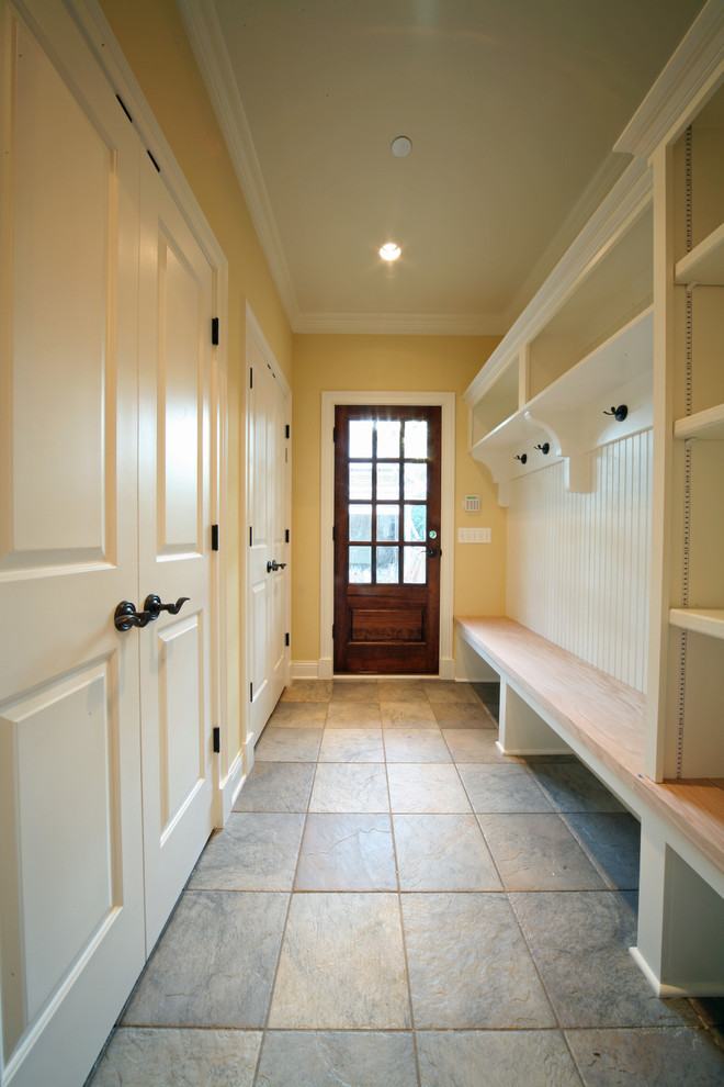 Inspiration pour une entrée traditionnelle de taille moyenne avec un vestiaire, un mur jaune, une porte simple et une porte en bois brun.