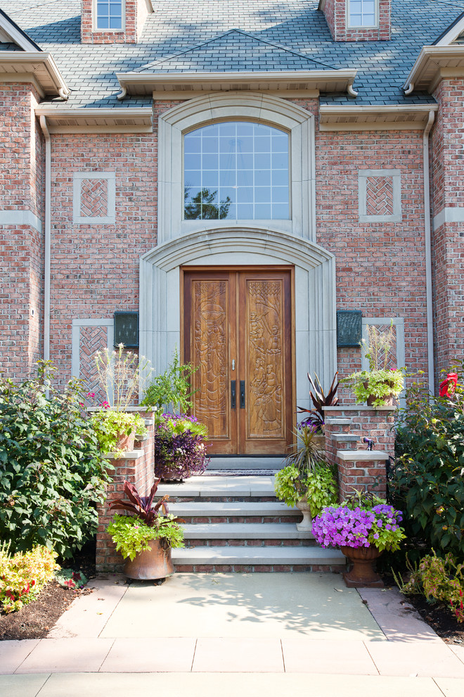 Idée de décoration pour une porte d'entrée tradition avec une porte double et une porte en bois brun.