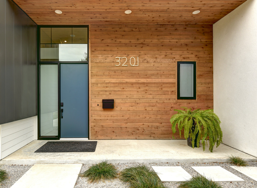 Exempel på en stor modern ingång och ytterdörr, med flerfärgade väggar, betonggolv, en enkeldörr och en blå dörr
