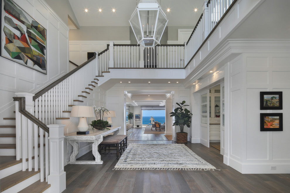 This is an example of a coastal foyer in Orange County with white walls, dark hardwood flooring and brown floors.