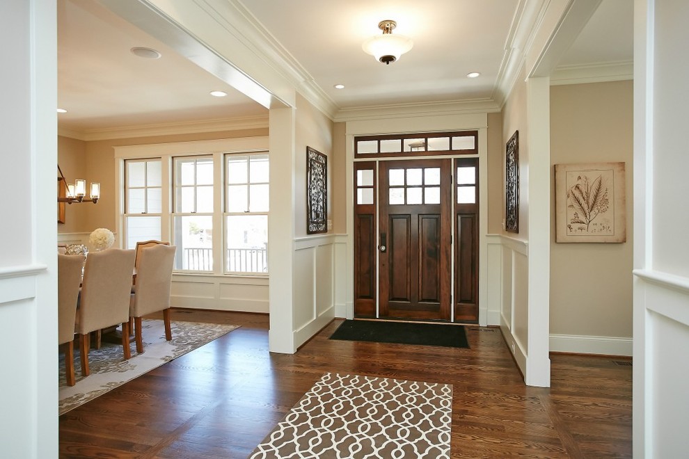 Aménagement d'un grand hall d'entrée craftsman avec un mur beige, parquet foncé, une porte simple, une porte en bois foncé et un sol marron.