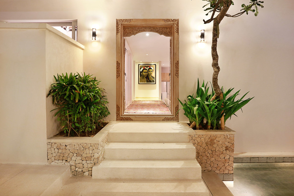 他の地域にある高級な中くらいなトロピカルスタイルのおしゃれな玄関ロビー (白い壁、大理石の床、木目調のドア) の写真