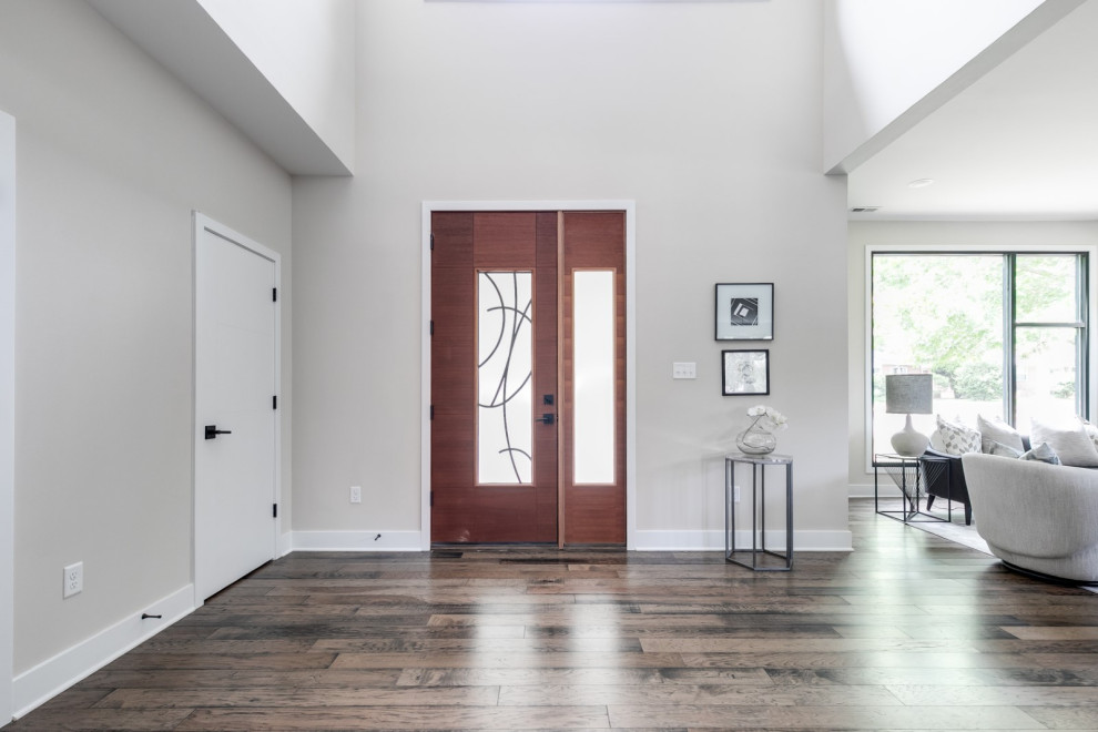 Foto di un ingresso moderno di medie dimensioni con pareti beige, pavimento in legno massello medio, una porta singola, una porta in legno scuro e pavimento marrone