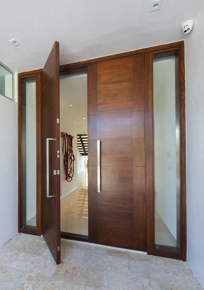 Modelo de puerta principal contemporánea grande con paredes blancas, suelo de piedra caliza, puerta doble y puerta de madera en tonos medios