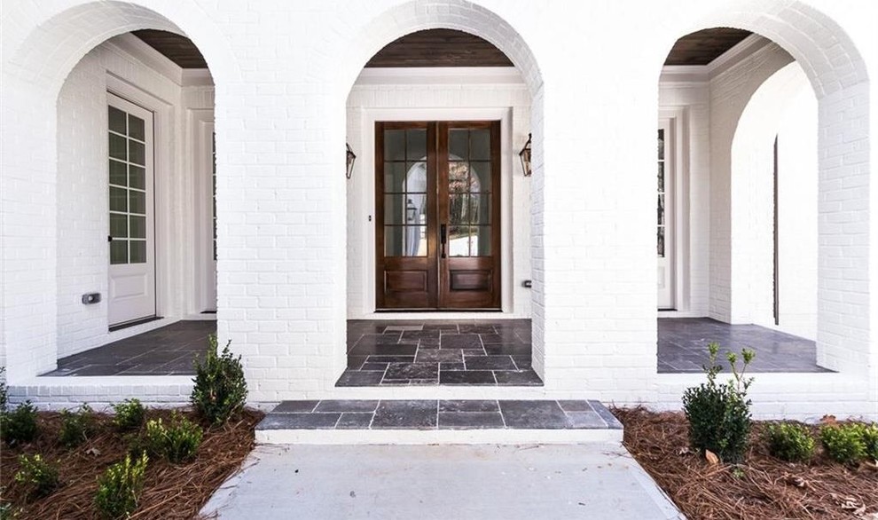 Große Landhaus Haustür mit weißer Wandfarbe, Kalkstein, Doppeltür, dunkler Holzhaustür und grauem Boden in Atlanta