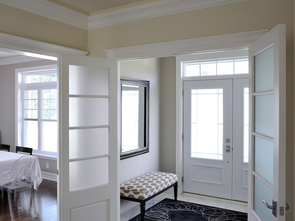 Aménagement d'une entrée classique avec un mur beige, un sol en carrelage de céramique, une porte double et une porte blanche.