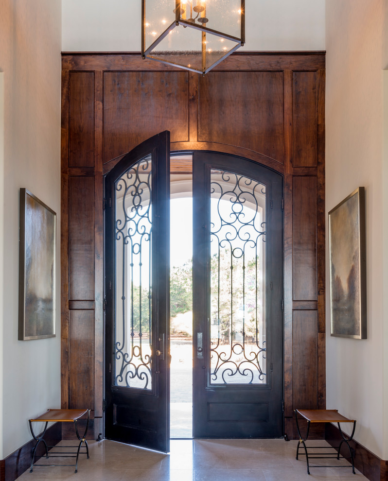 Diseño de puerta principal mediterránea grande con paredes blancas, suelo de piedra caliza, puerta doble y puerta de madera oscura