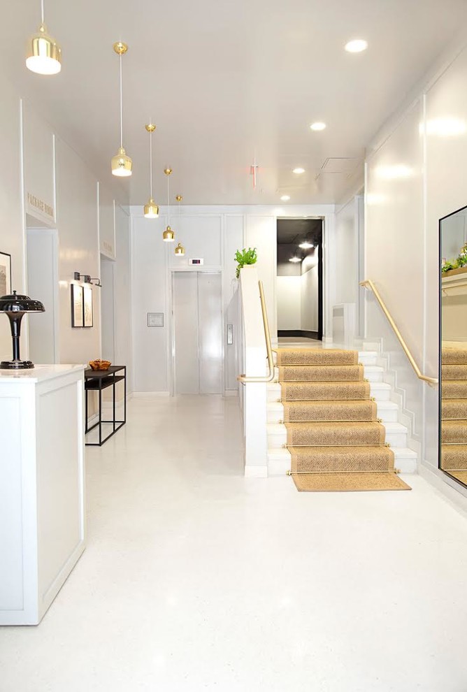 This is an example of a medium sized contemporary foyer in New York with white walls and white floors.