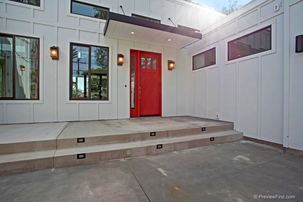 На фото: большая входная дверь в стиле кантри с белыми стенами, одностворчатой входной дверью и красной входной дверью с