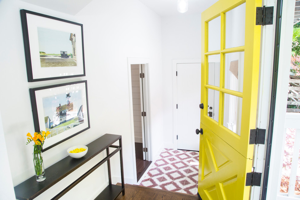 Lantlig inredning av en entré, med vita väggar, en tvådelad stalldörr och en gul dörr