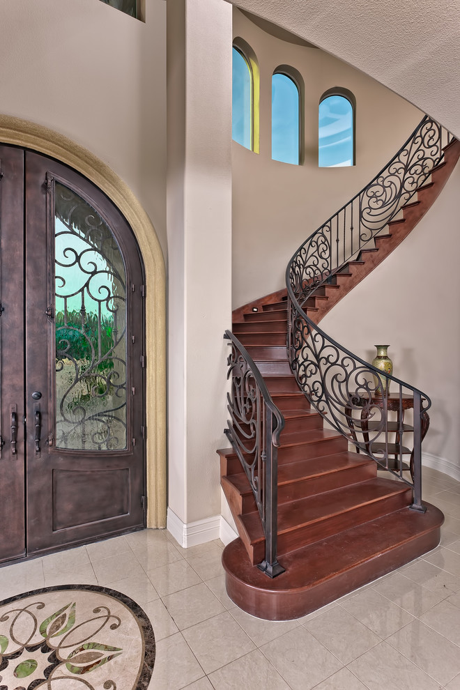 Modelo de puerta principal mediterránea de tamaño medio con paredes beige, puerta doble, puerta de madera oscura y suelo beige