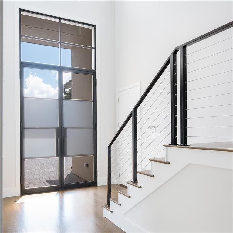 Diseño de puerta principal moderna pequeña con paredes blancas, suelo de madera clara, puerta doble, puerta de vidrio y suelo marrón