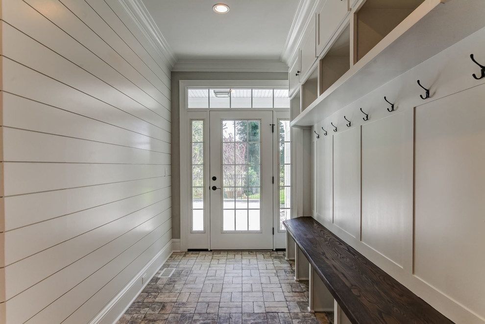Aménagement d'une entrée classique avec un vestiaire, un mur blanc, une porte simple, une porte blanche et un sol marron.