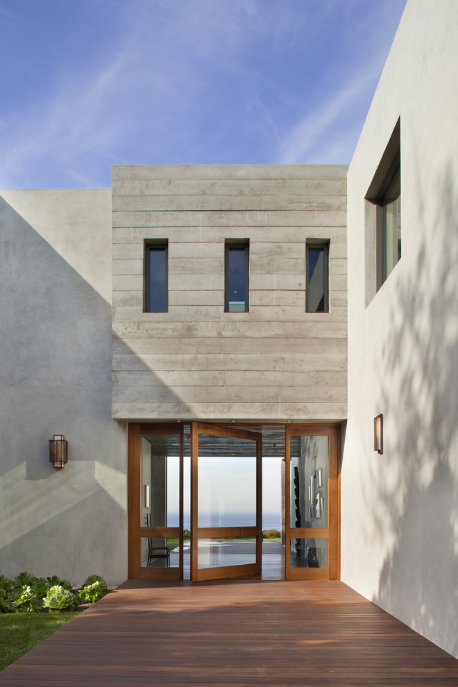 Imagen de entrada minimalista con puerta pivotante y puerta de vidrio
