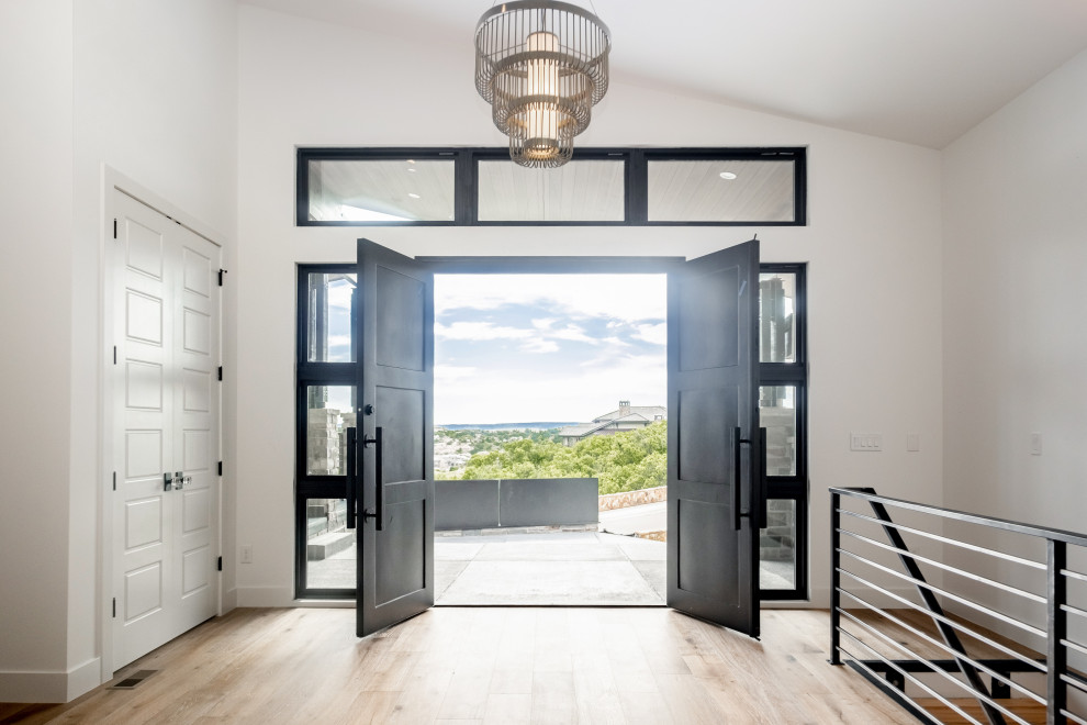 Ejemplo de puerta principal minimalista con paredes blancas, suelo de madera clara, puerta doble y puerta negra