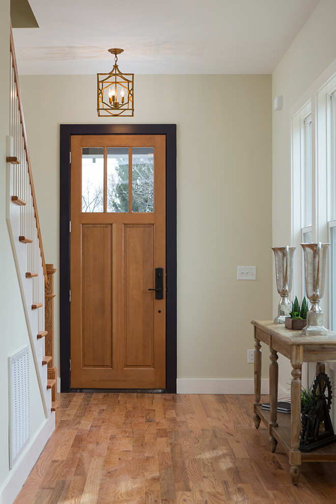 Diseño de hall industrial de tamaño medio con suelo de madera en tonos medios, puerta simple y puerta de madera clara