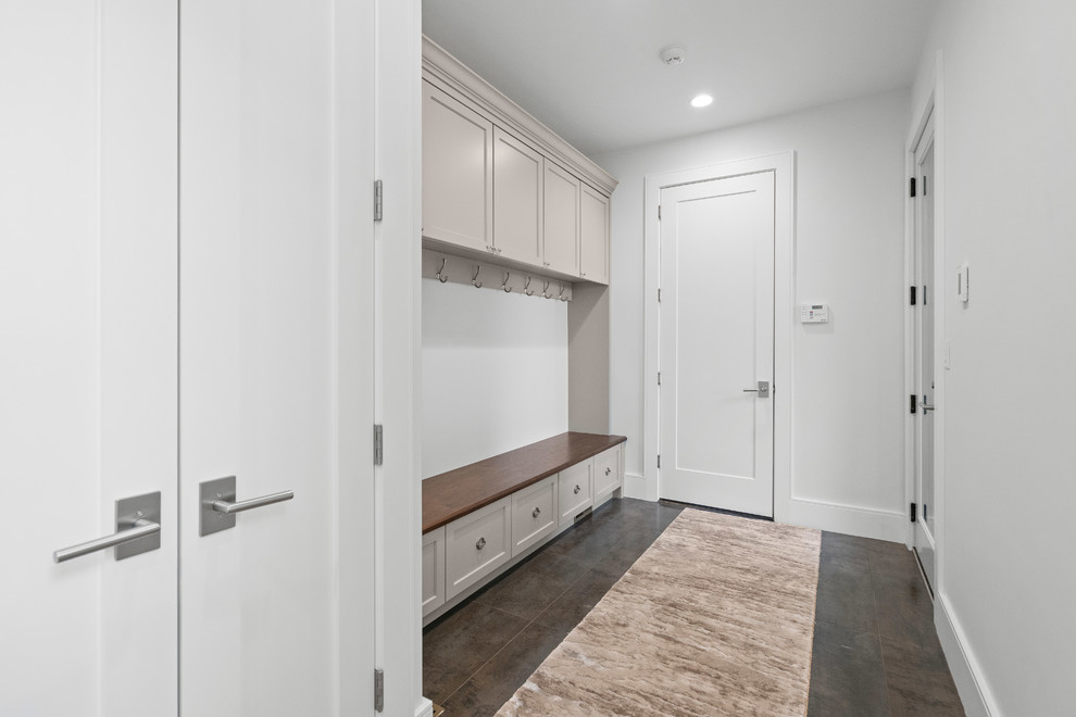 Large minimalist porcelain tile and multicolored floor entryway photo in Boston with white walls and a dark wood front door