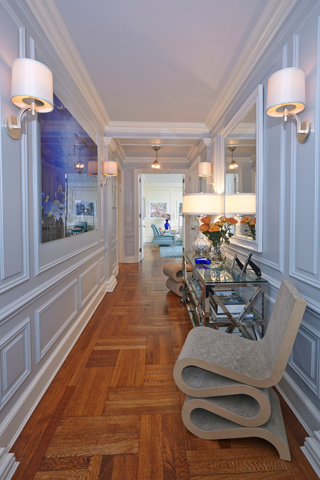 Large modern hallway in New York with blue walls, medium hardwood flooring and brown floors.