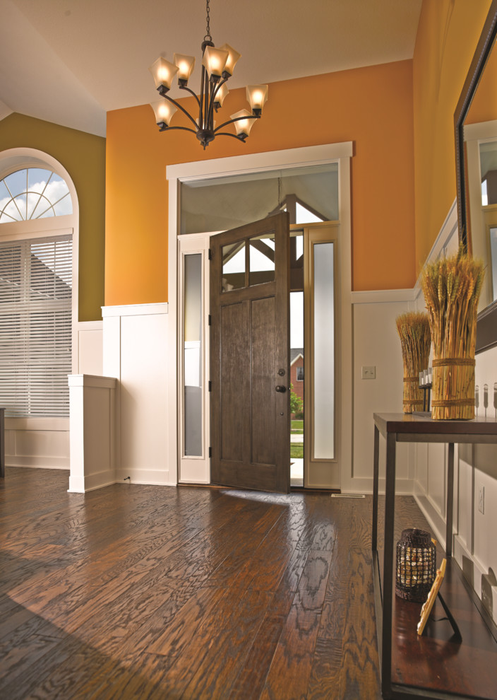 Пример оригинального дизайна: прихожая в стиле неоклассика (современная классика) с одностворчатой входной дверью, входной дверью из темного дерева, оранжевыми стенами и темным паркетным полом