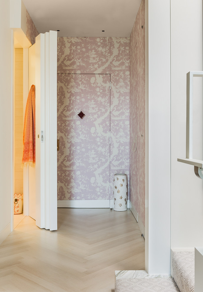 Diseño de hall contemporáneo con paredes rosas, suelo de madera clara y puerta simple